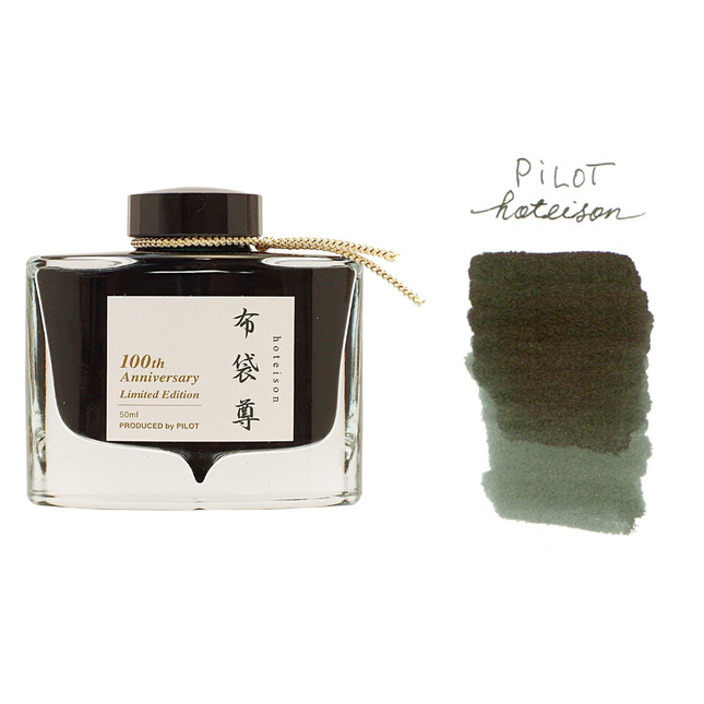 A bottle of Pilot Iroshizuku fountain pen ink with a label indicating it is a 100th Anniversary Limited Edition. Accompanied by a swatch showing the black-green color of the ink.